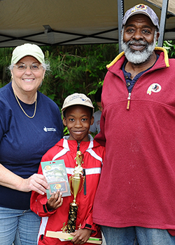 WSSC Community Outreach Coordinator Sandy August with Colin Parker, Jr., winner of the heaviest fish contest and his grandfather, Norman Morris, WSSC retiree and longtime steward of the watershed.