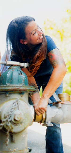 A young woman attaching a fire hydrant meter to a fire hydrant