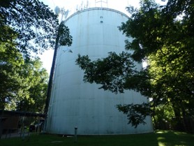 Greenbelt Standpipe, surrounded by trees and backlit slightly by sunshine.