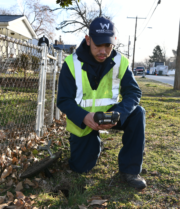 Meter Reader kneeling at a meter to get a reading