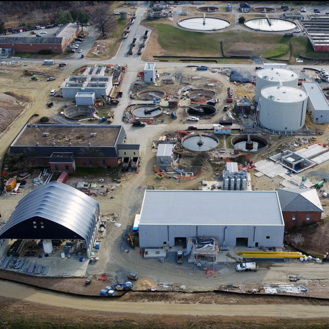 At the bottom of the photo on the backside of the Solids Building, those long yellow metal pieces are major parts of the bridge crane rails which will be constructed inside the building.  The bridge crane is mounted high along the walls inside the building and is used to move heavy pieces of equipment and other material.
