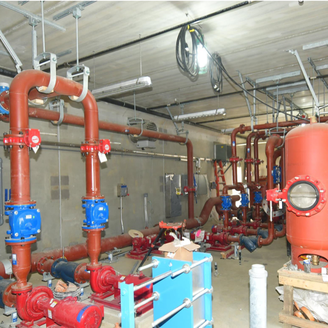 This photo is inside the Medium Temperature Hot Water Building showing the pumps, process piping and mechanical work.