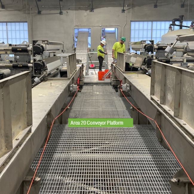  Workers on the mezzanine level in the Solids Building inspecting the Belt Filter Presses.  The conveyors leading to the Cake Storage Facility are behind them.