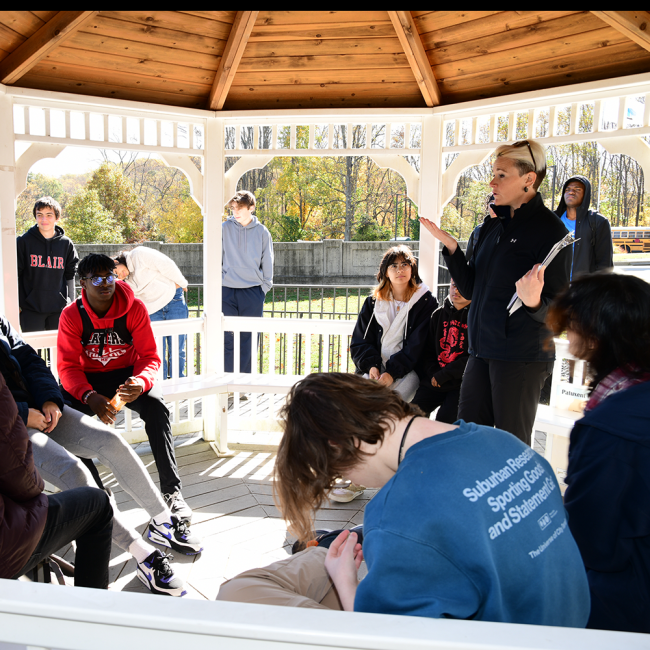 instructing students on the day's plan in the gazebo