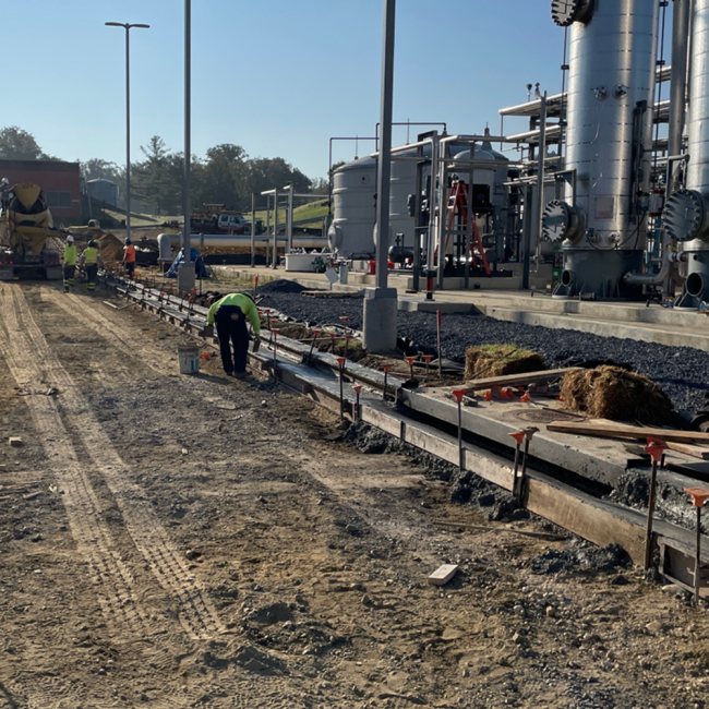 Concrete finisher working on the curb and gutter adjacent the gas cleaning facility.