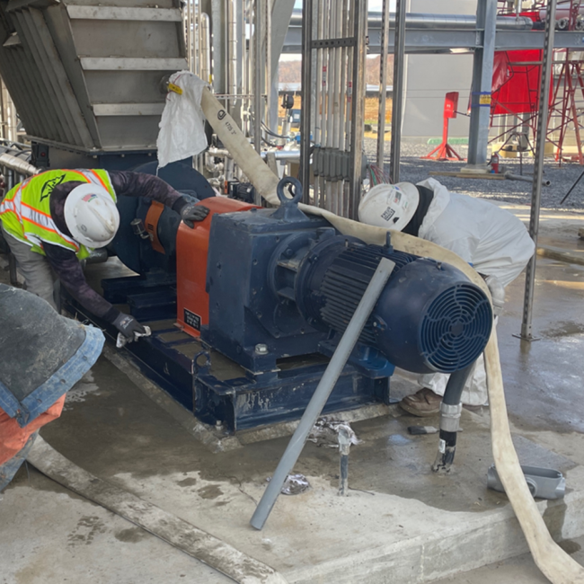 Workers are grouting in the bases for the pumps at the Cake Receiving Facility.