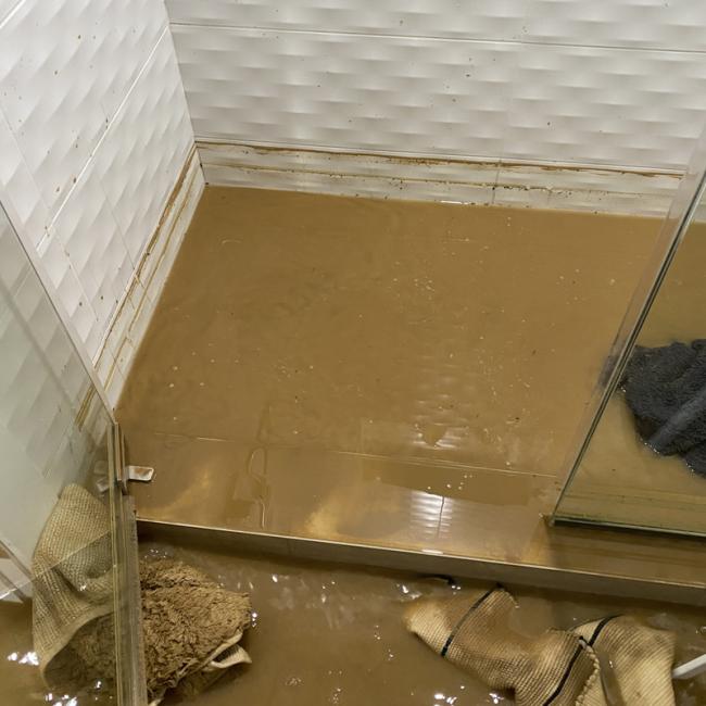 Shower stall filled with sewage and towels. 