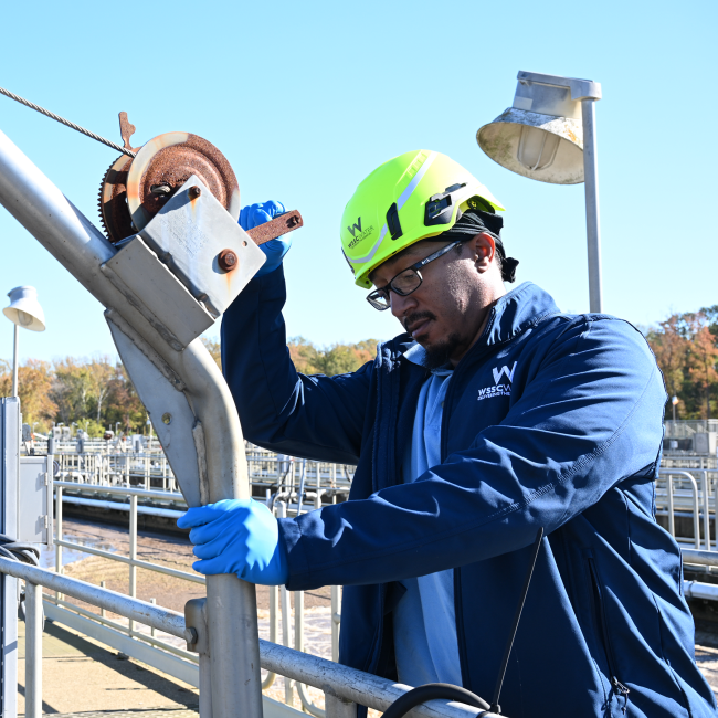 Wastewater Operator lowering a bucket to test wastewater
