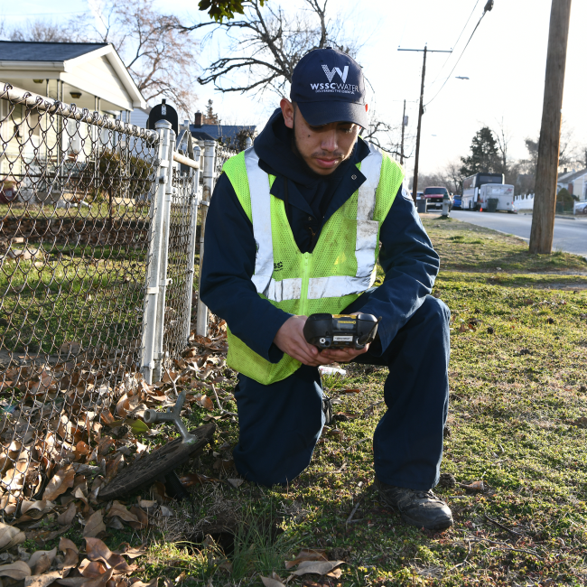 Meter Reader kneeling at a meter to get a reading
